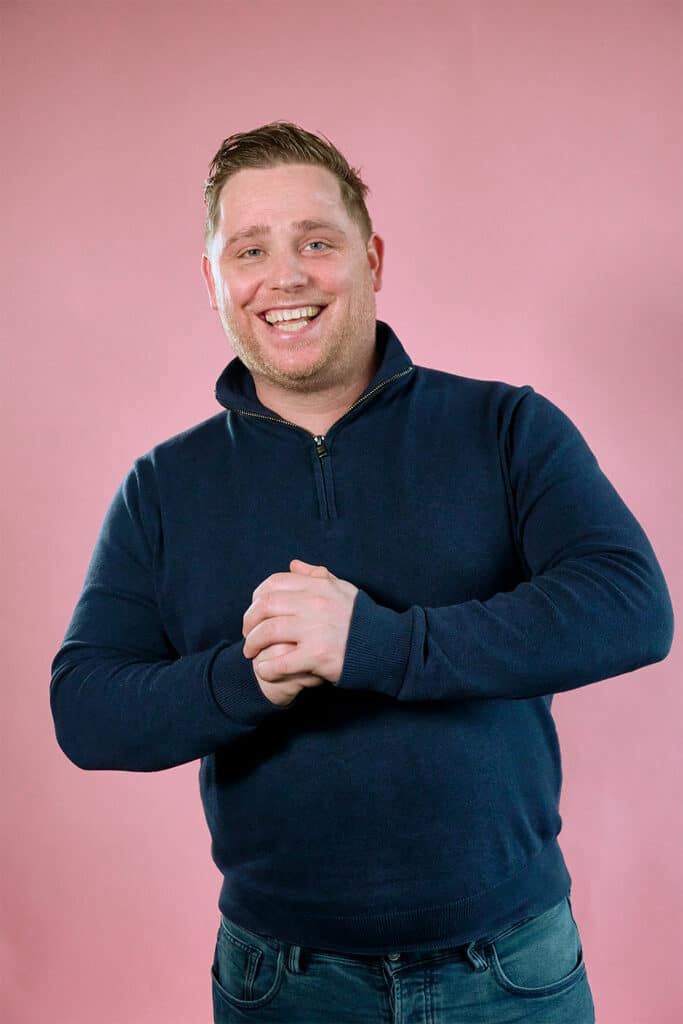 Tijmen op een roze achtergrond met een donker blauwe trui en spijkerbroek