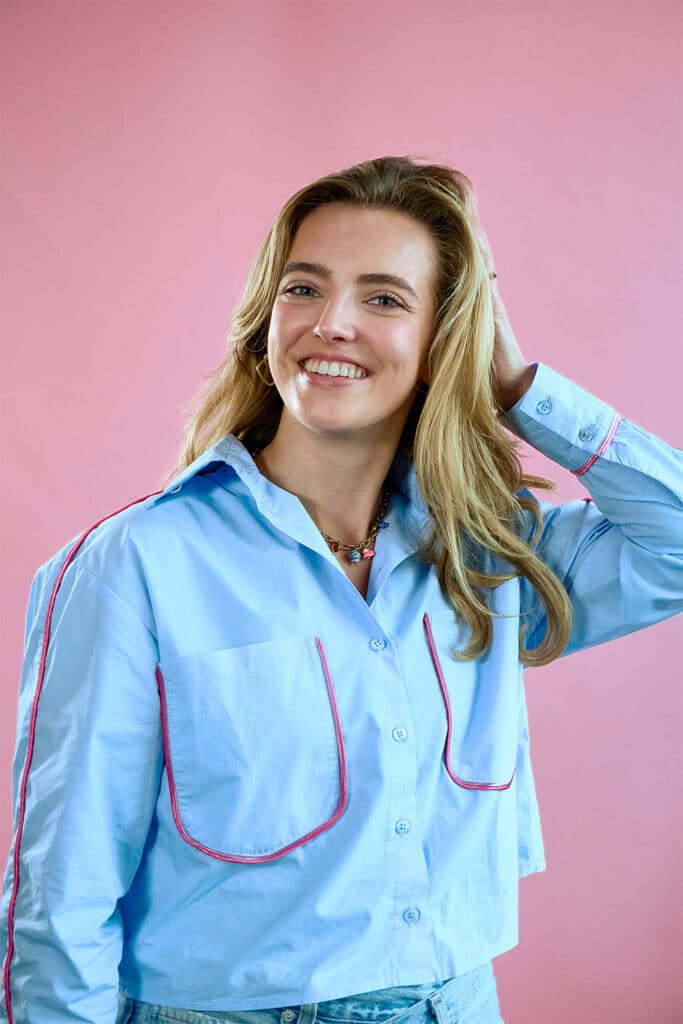 Sanne op een roze achtergrond met een lichtblauwe blouse