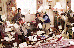 Een gif in een woonkamer met een gezin van vier personen, er vliegen allemaal a4tjes door de lucht heen.