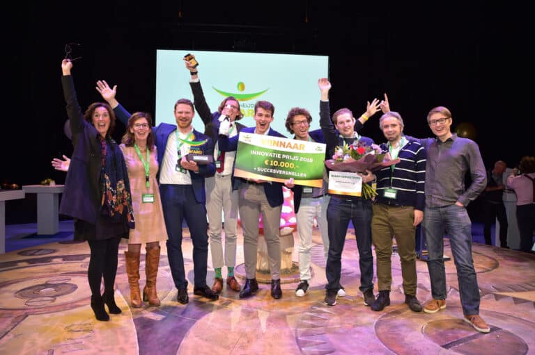 Een groep mensen die een innovatie prijs hebben gewonnen. Ze zijn aan het juichen, het zijn 7 mannen en 2 vrouwen. Van het CSU