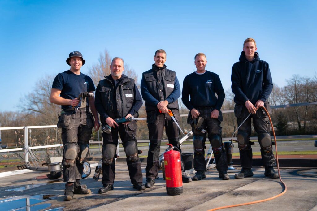 Vijf collega’s van DAKaccent met dakdekkersgereedschap op een dak.
