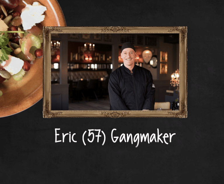 Portret van Eric (57), een vrolijke medewerker in een restaurant, gekleed in een zwarte koksjas en muts. Hij staat lachend in een sfeervol ingerichte ruimte met warme verlichting en chique decor. De tekst ‘Gangmaker’ benadrukt zijn energieke en sociale karakter