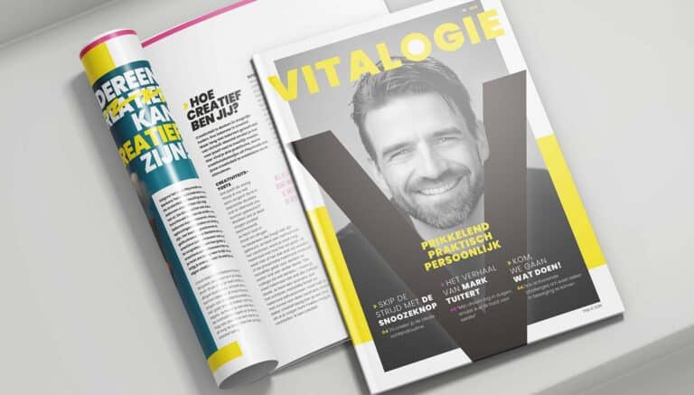 Een strak vormgegeven magazine met de titel "VITALOGIE" ligt op een witte ondergrond. De cover toont een zwart-wit portret van een lachende man, met gele en witte typografie die kernwoorden als "Prikkelend, Praktisch, Persoonlijk" benadrukt. Een opengeslagen pagina naast het magazine bevat een artikel over creativiteit, met een speelse en kleurrijke lay-out.